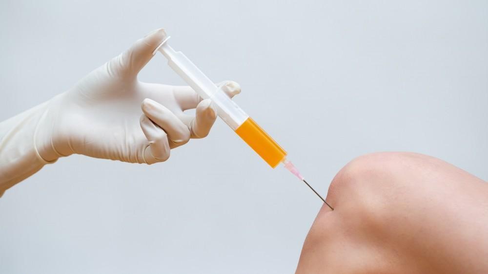 A doctor administering Platelet-Rich Plasma (PRP) injection into a patient's knee.