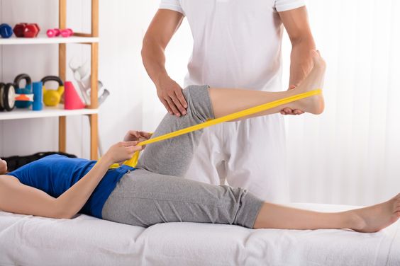 A physical therapist assisting a patient with knee exercises post-surgery.